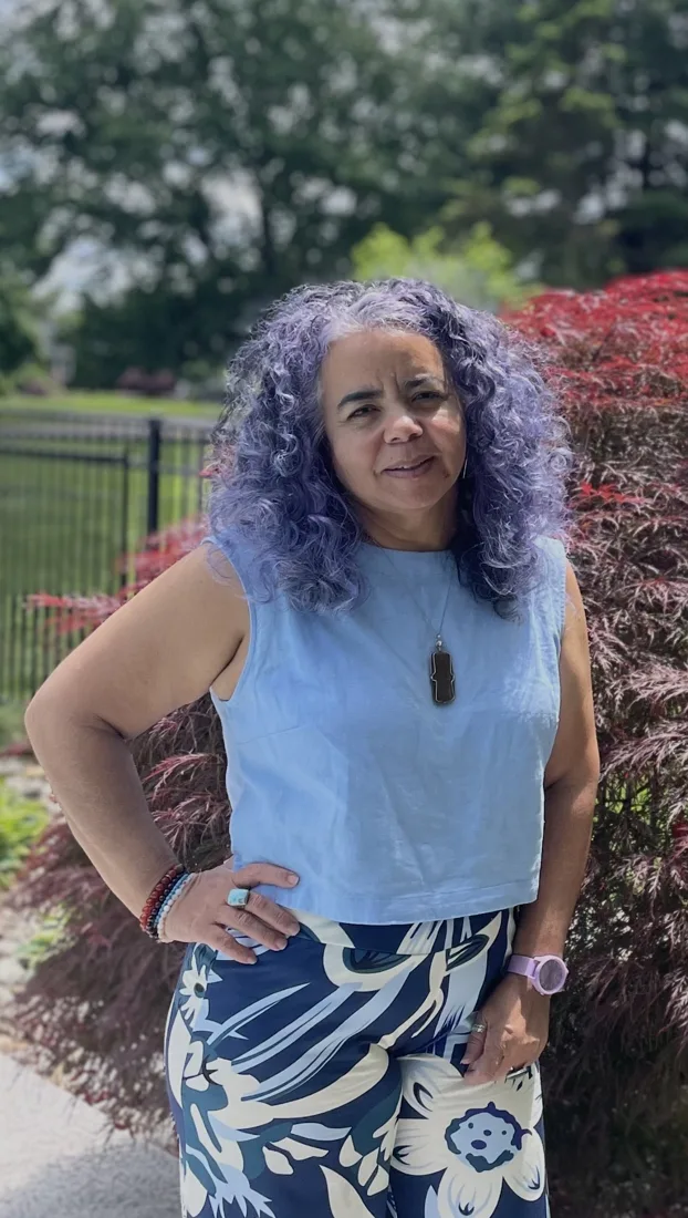 Martha smiling in a garden, hand on hip, with lavender curls
